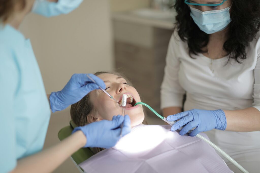 Patient undergoing wisdom tooth extraction sedation at a dental clinic with dentist and assistant performing the procedure
