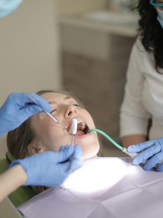 Patient undergoing wisdom tooth extraction sedation at a dental clinic with dentist and assistant performing the procedure
