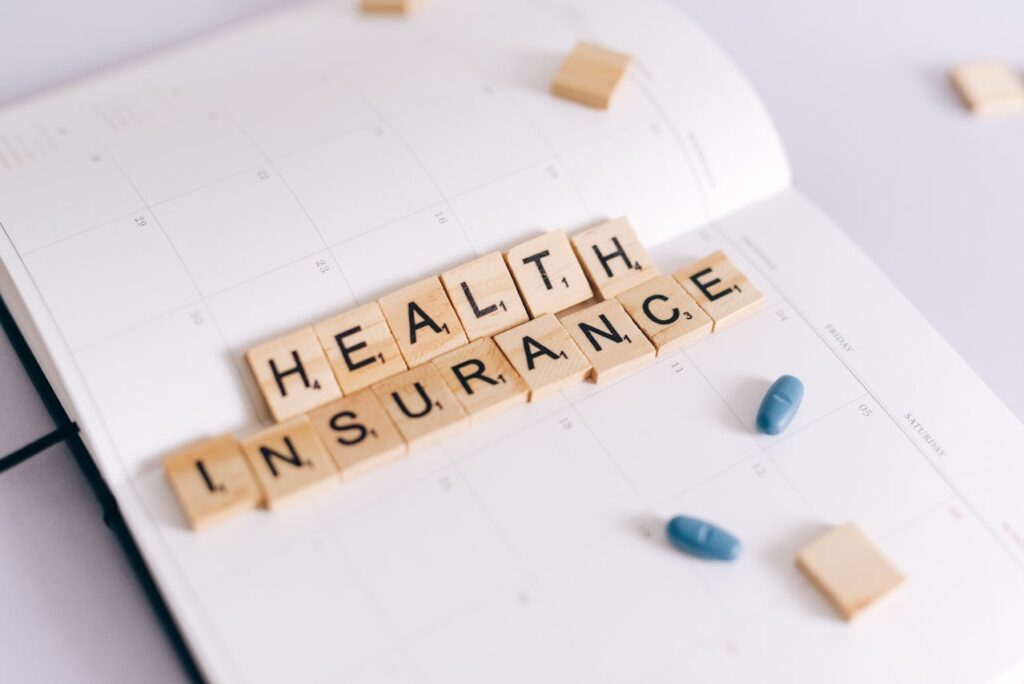 Health insurance concept with calendar pages, medication, and letter tiles spelling &ldquo;health insurance,&rdquo; representing rising home health care insurance cost and long-term care planning.
