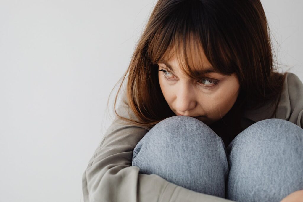 Woman sitting curled up looking overwhelmed, showing how to recover from burnout and emotional exhaustion