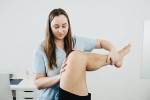 Physical therapist examining a patient&rsquo;s knee to show how to relieve knee pain and improve joint mobility