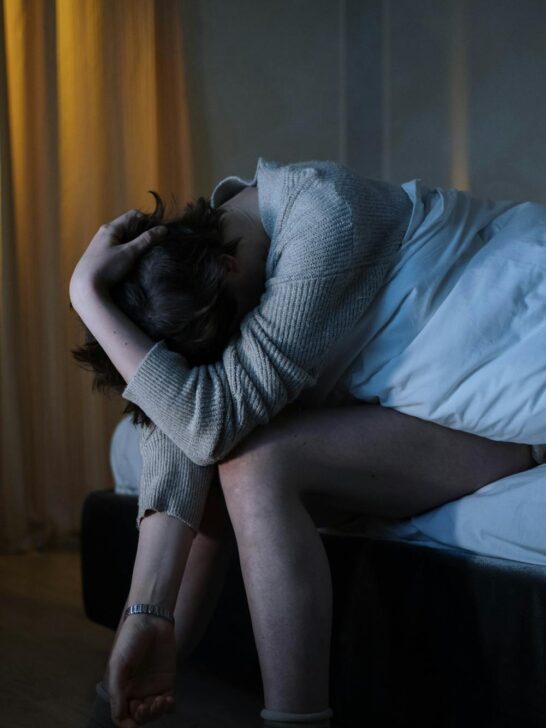 Person sitting on the edge of a bed feeling overwhelmed, representing treatment for anxiety and depression and emotional distress