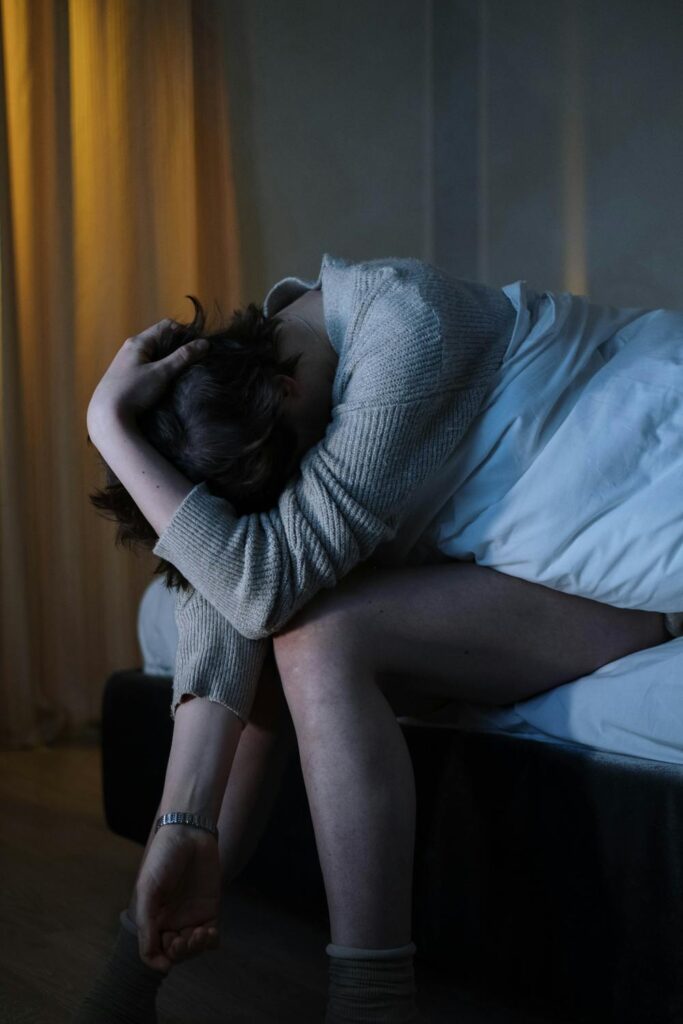 Person sitting on the edge of a bed feeling overwhelmed, representing treatment for anxiety and depression and emotional distress