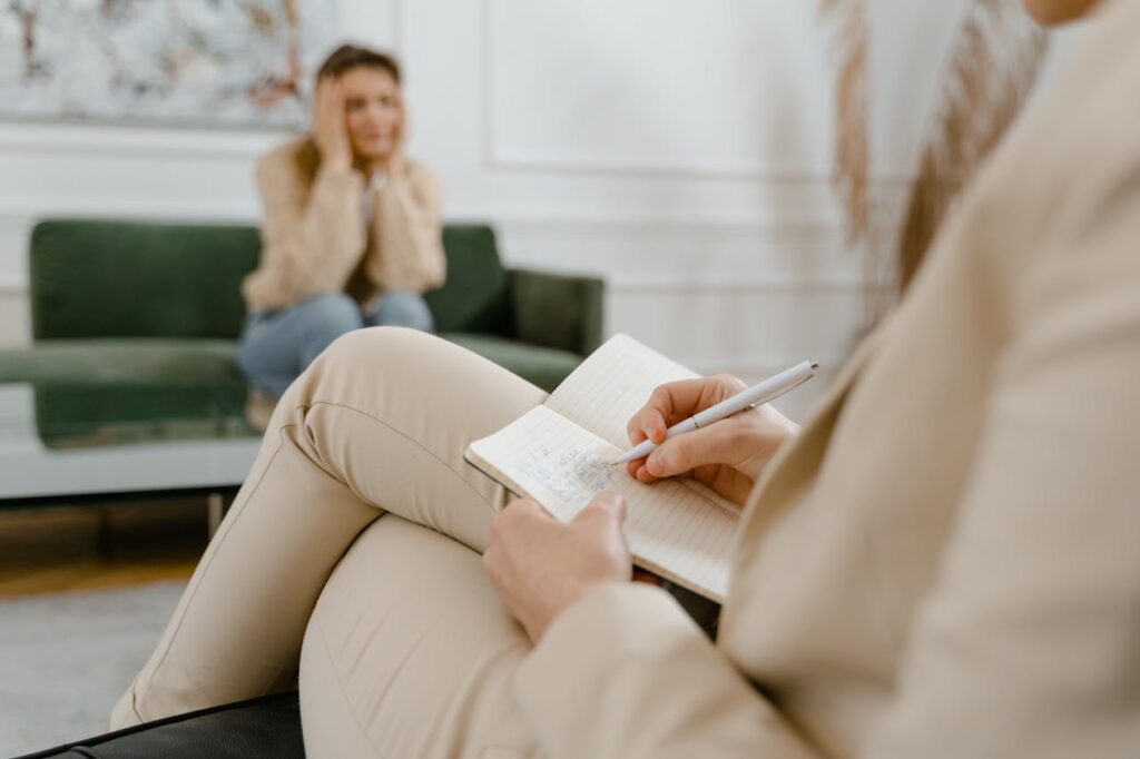 Therapist taking notes during a counseling session with a patient discussing mental health concerns