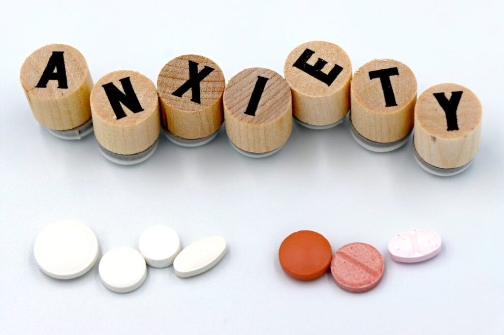 Wooden blocks spelling anxiety with pills below, representing treatment for anxiety and depression and mental health care options