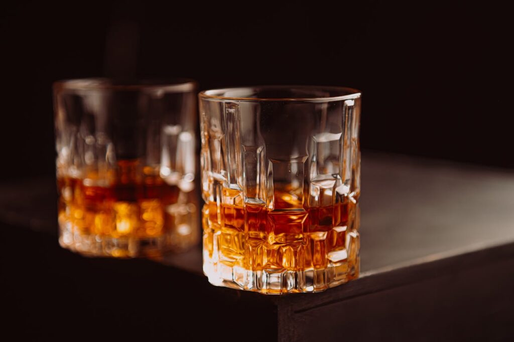 Two glasses of whiskey resting on a dark wooden surface, perfect for showcasing a refined whiskey collection and cozy evening atmosphere.