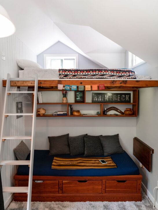 Small bedroom with a loft bed, built-in shelving, storage drawers, and a space-saving layout designed to maximize floor space and functionality.