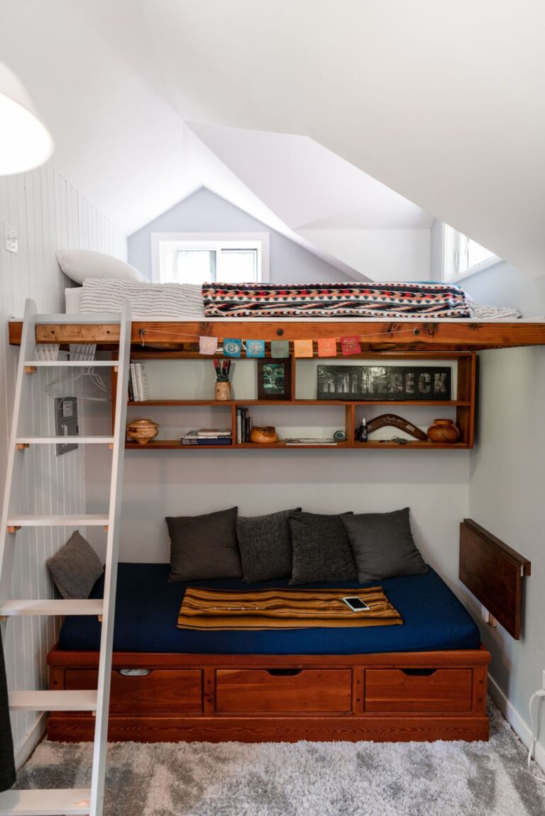 Small bedroom with a loft bed, built-in shelving, storage drawers, and a space-saving layout designed to maximize floor space and functionality.