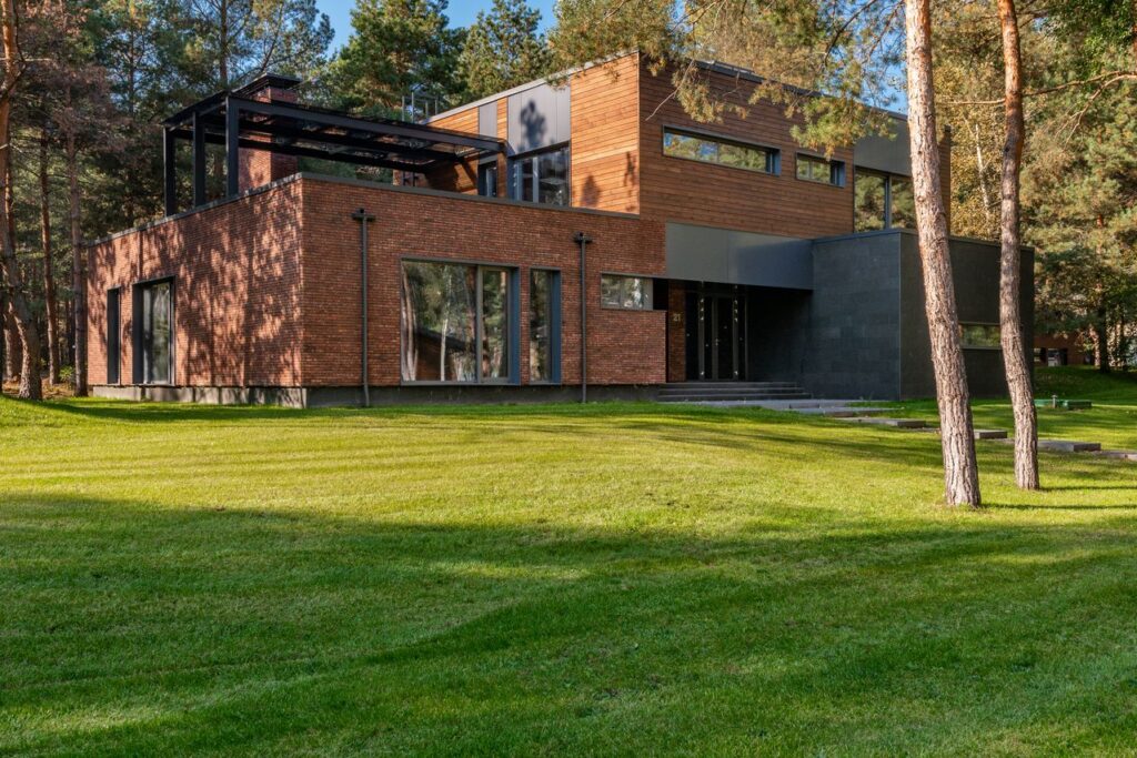 Home exterior maintenance helps keep this modern brick and wood house looking clean, attractive, and well cared for with a manicured lawn and tidy landscaping.