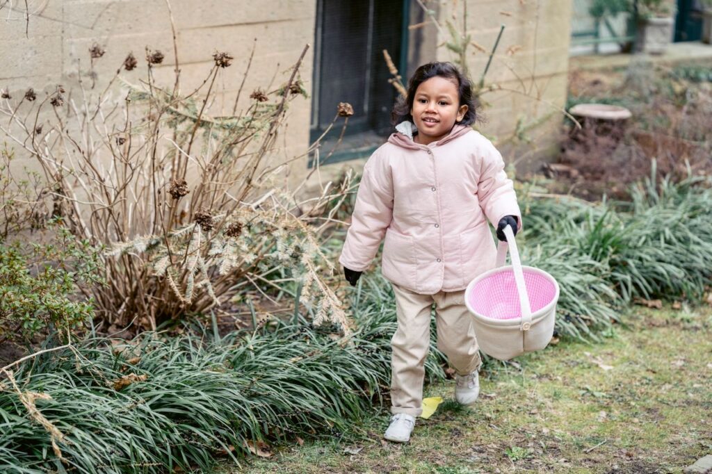 Child carrying a basket while exploring a backyard in search of hidden treasures during a family outdoor adventure.