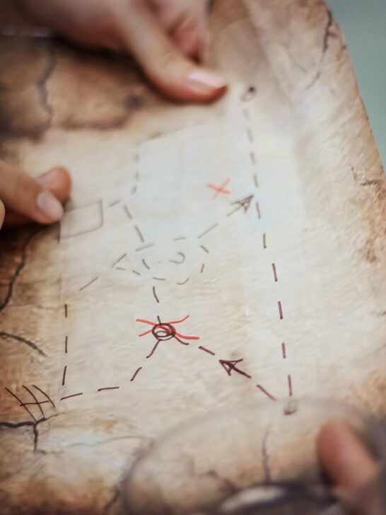 Backyard treasure hunt map with hands pointing to a marked route leading to hidden treasure.