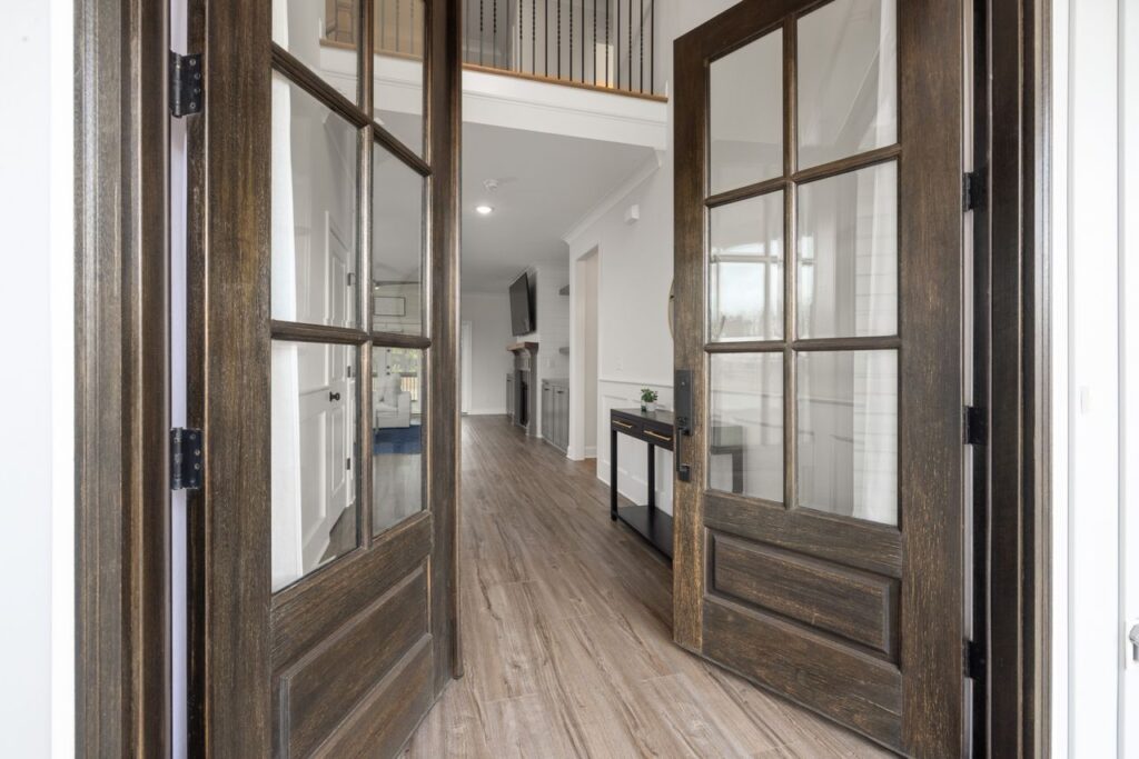 Rustic wood double front doors with large glass panels opening into a bright modern entryway