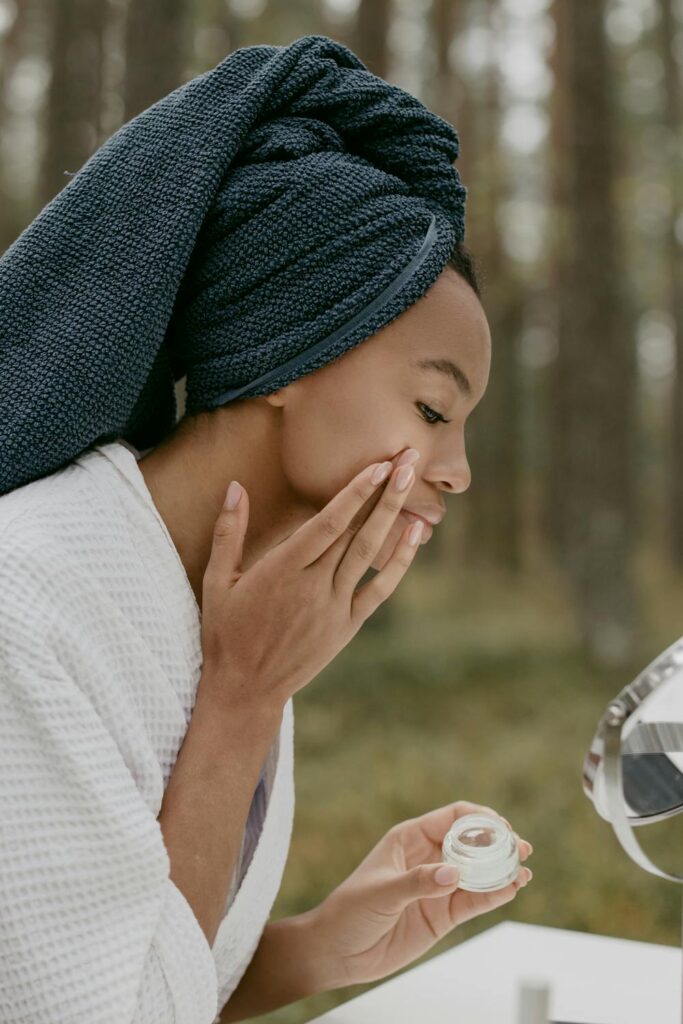 Person applying skincare product while looking in a mirror, highlighting how skin quality and volume can influence facial balance and the appearance of facial symmetry.