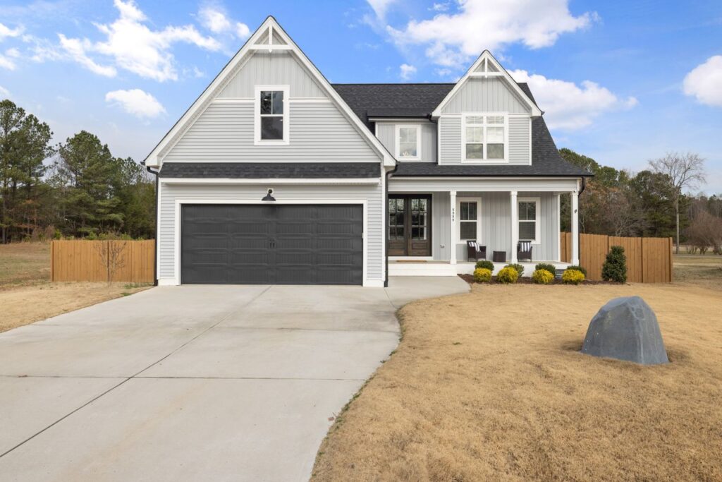Exterior view of a newly constructed home featuring modern architecture, a two-car garage, and a spacious front yard.