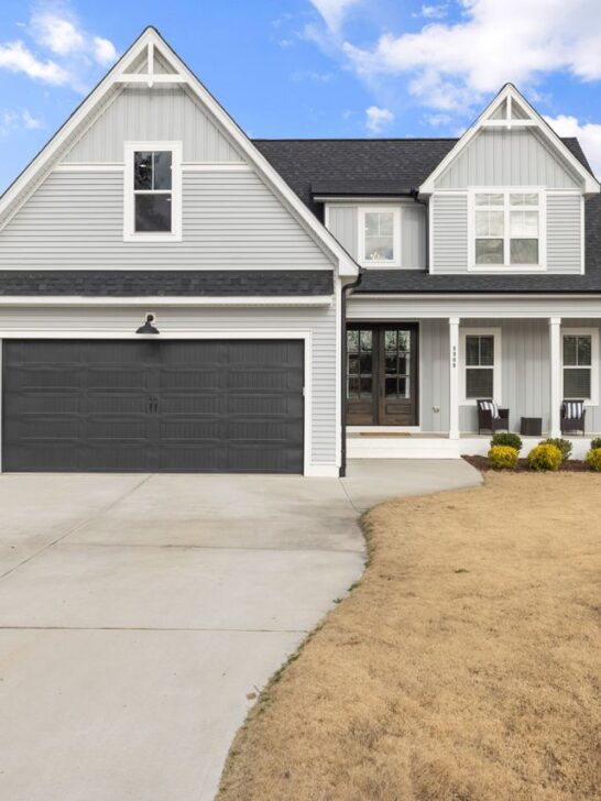 Exterior view of a newly constructed home featuring modern architecture, a two-car garage, and a spacious front yard.