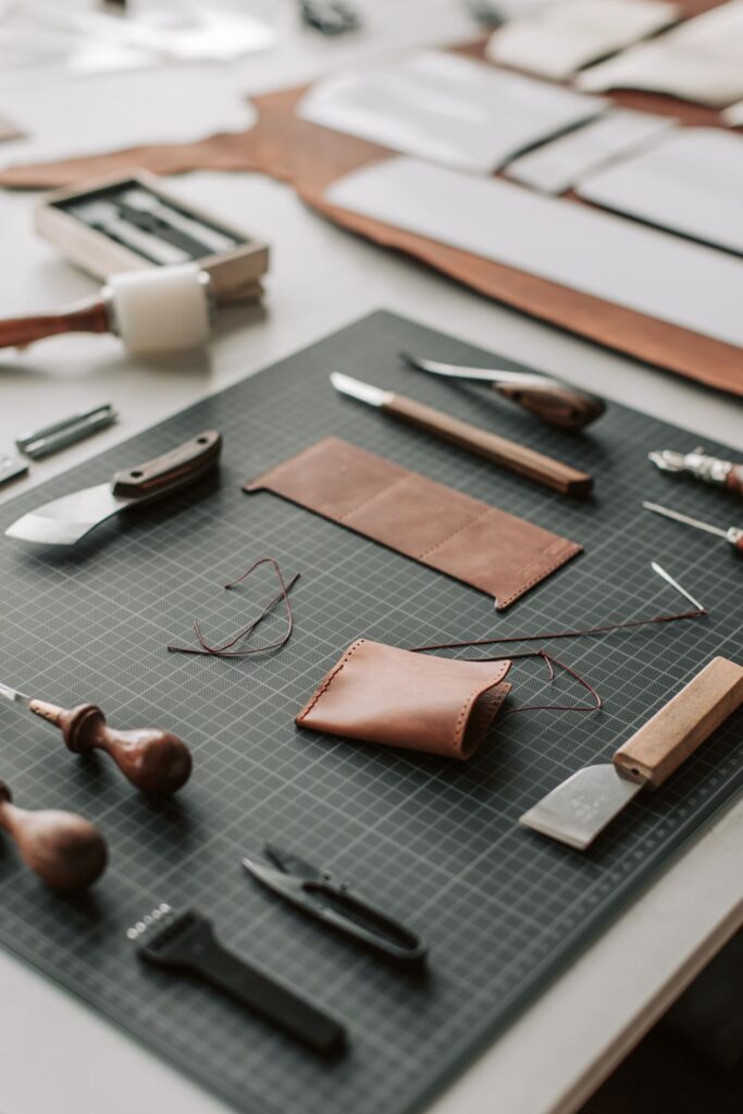 Leather crafting tools and materials arranged on a worktable for creating handmade accessories and personalized gifts