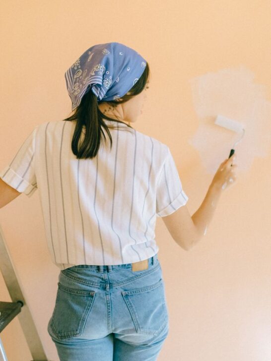 Homeowner painting an interior wall during a DIY project while preparing to sell your house fast without major renovations.