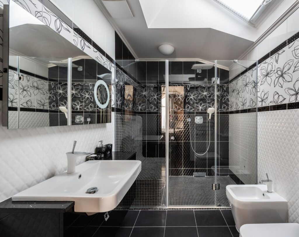 Contemporary black-and-white bathroom with a spacious walk-in shower, glass enclosure, and decorative tile accents.