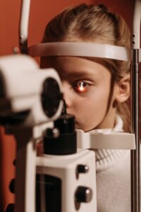 Child undergoing a children's vision check with a slit lamp eye exam machine during a routine pediatric eye appointment.