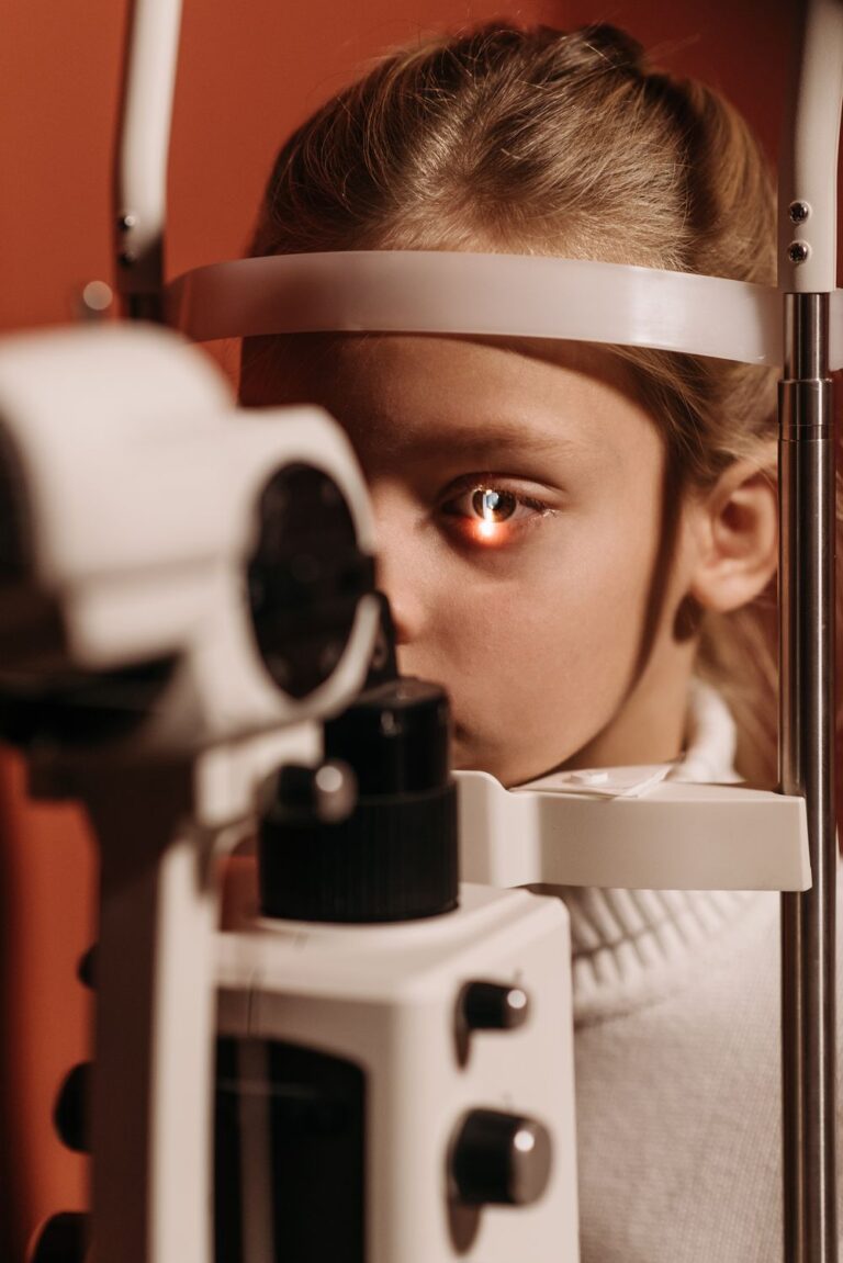 Child undergoing a children's vision check with a slit lamp eye exam machine during a routine pediatric eye appointment.