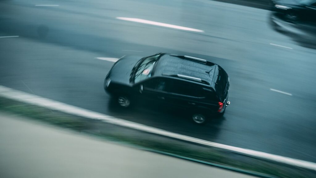 Black SUV driving on a wet roadway, demonstrating confident handling and everyday performance in rainy driving conditions.