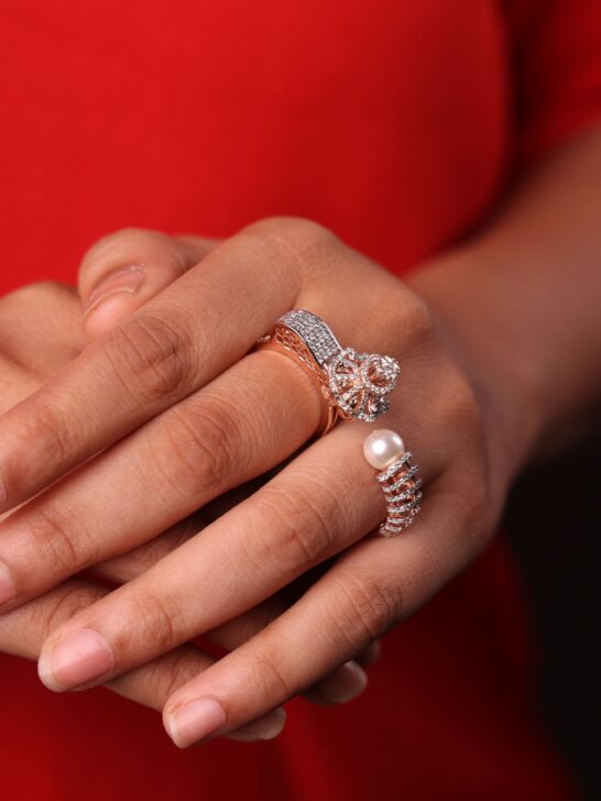 Woman wearing elegant rose gold and diamond rings with a pearl accent ring on her hand.