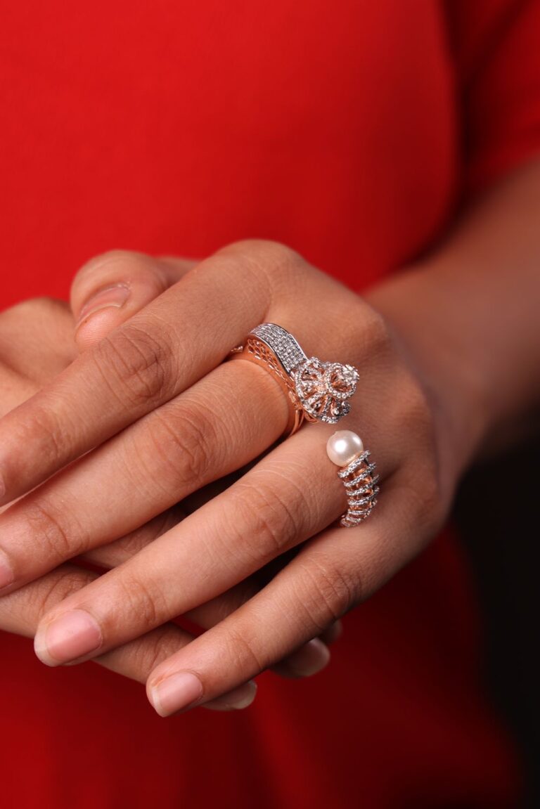 Woman wearing elegant rose gold and diamond rings with a pearl accent ring on her hand.