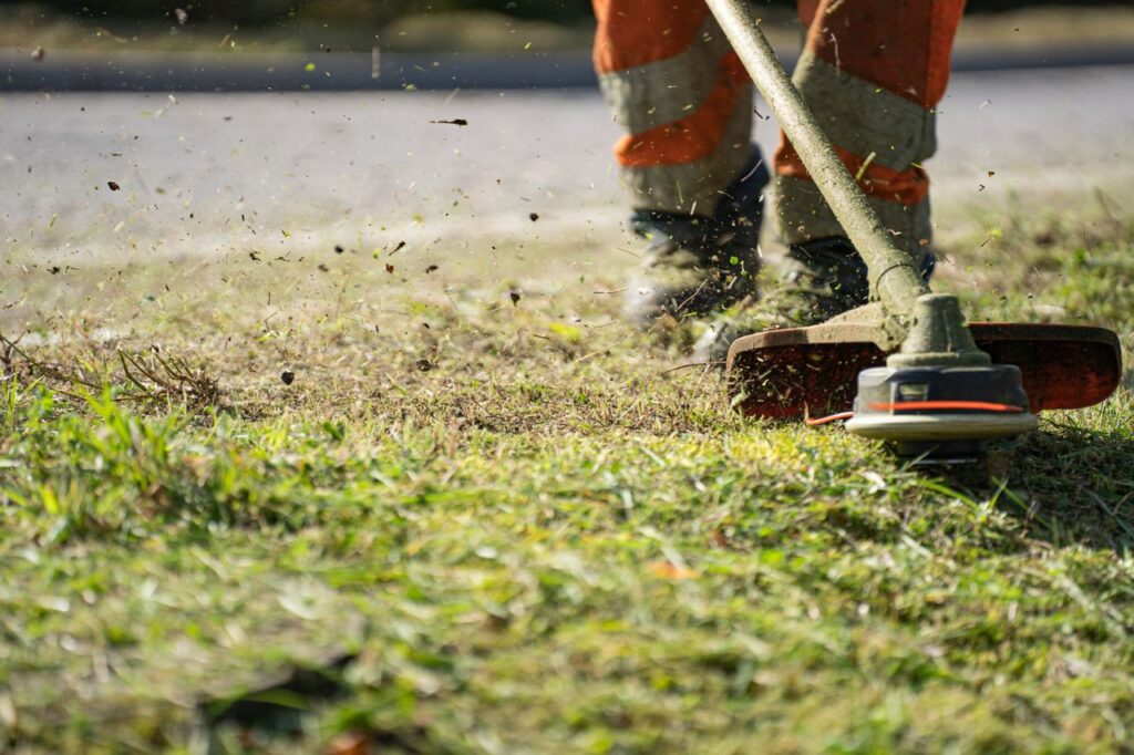 Trimming grass along a lawn edge with a string trimmer during routine yard maintenance.