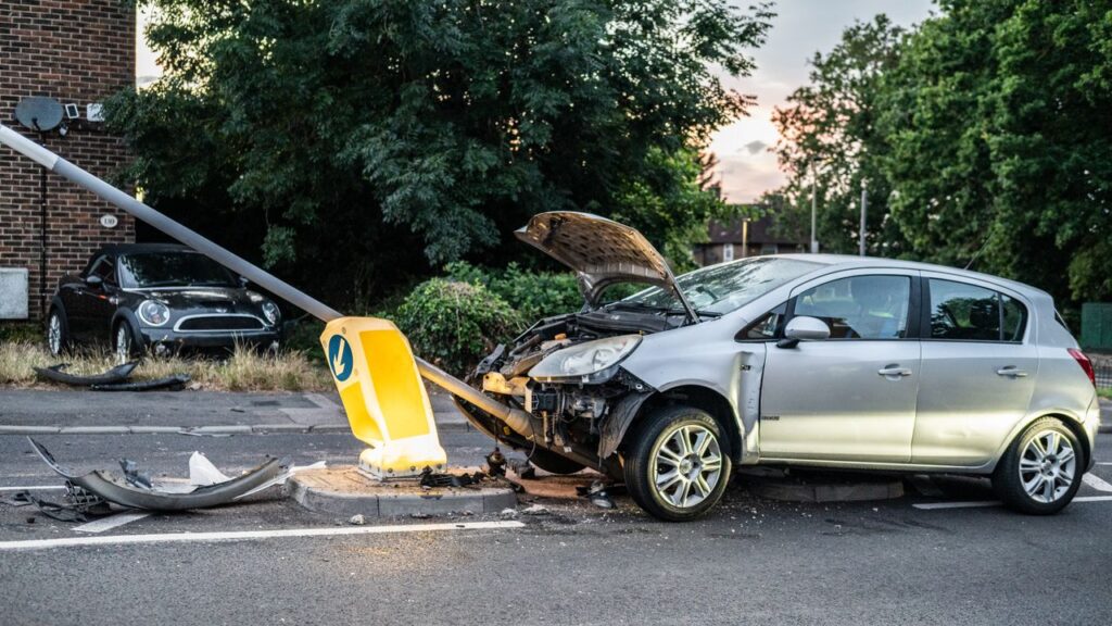 Delayed car accident injuries after a crash involving a damaged silver car that struck a roadside traffic sign.