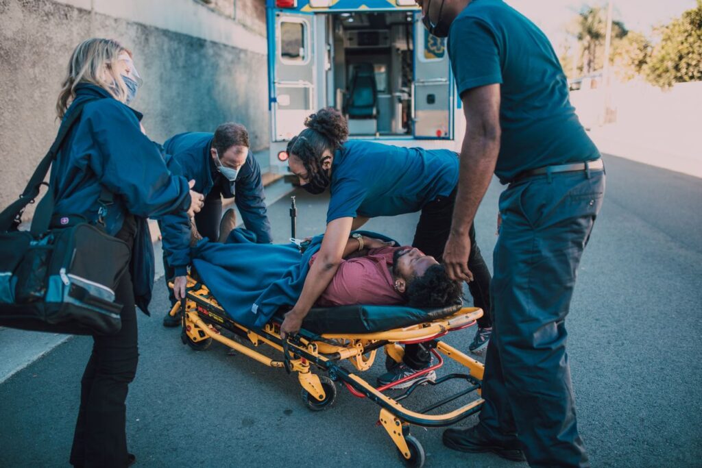 Emergency medical responders loading an injured person onto a stretcher after a motor vehicle accident for evaluation and treatment.