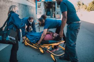 Emergency medical responders loading an injured person onto a stretcher after a motor vehicle accident for evaluation and treatment.