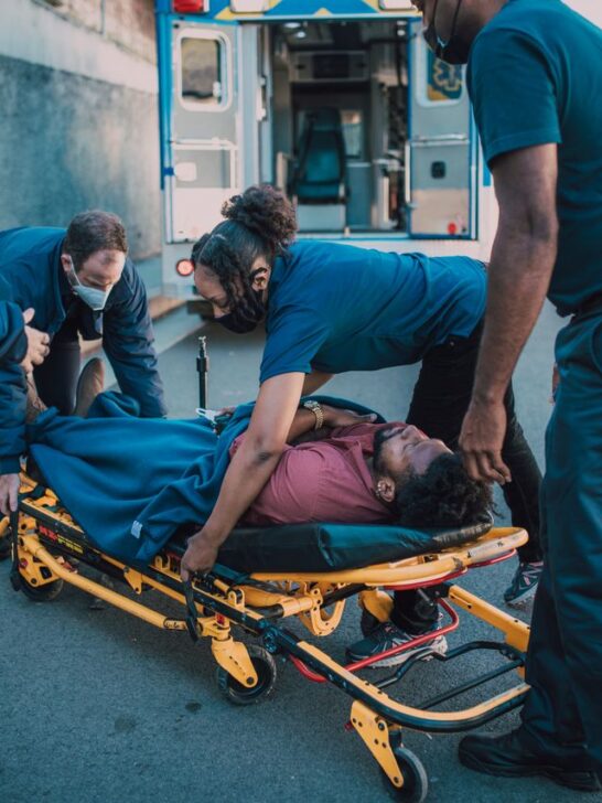 Emergency medical responders loading an injured person onto a stretcher after a motor vehicle accident for evaluation and treatment.