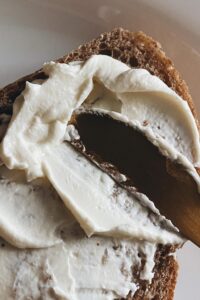 Fresh homemade butter from an electric butter churn spread onto a slice of rustic bread.