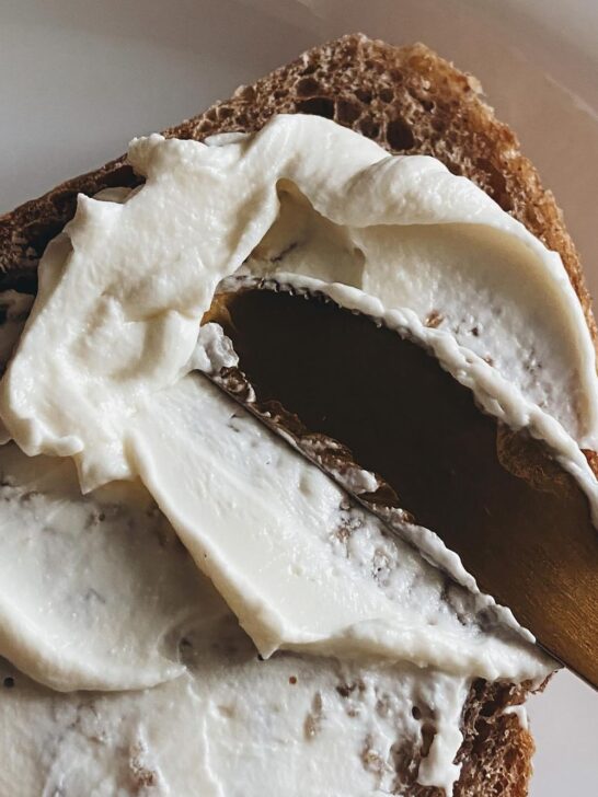 Fresh homemade butter from an electric butter churn spread onto a slice of rustic bread.