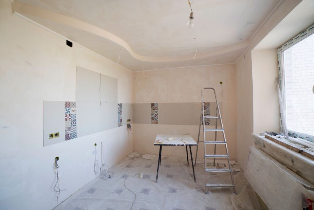 Home renovation planning for a kitchen remodel with construction materials, tools, and unfinished walls.