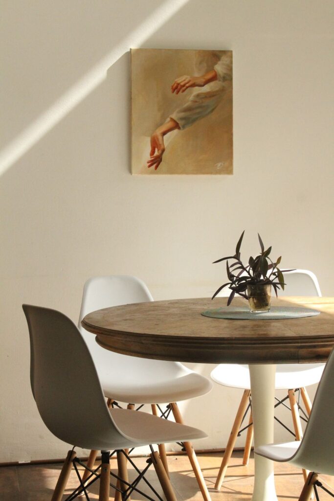 Round wooden dining table with white chairs in a bright dining room, creating a comfortable and inviting space for everyday meals.