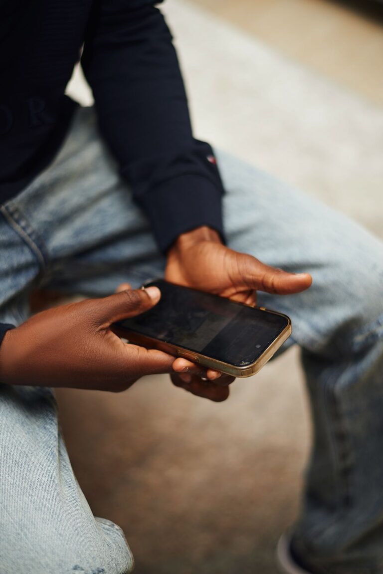 Person holding a smartphone while sitting down, illustrating how to reduce screen time and create healthier phone habits.