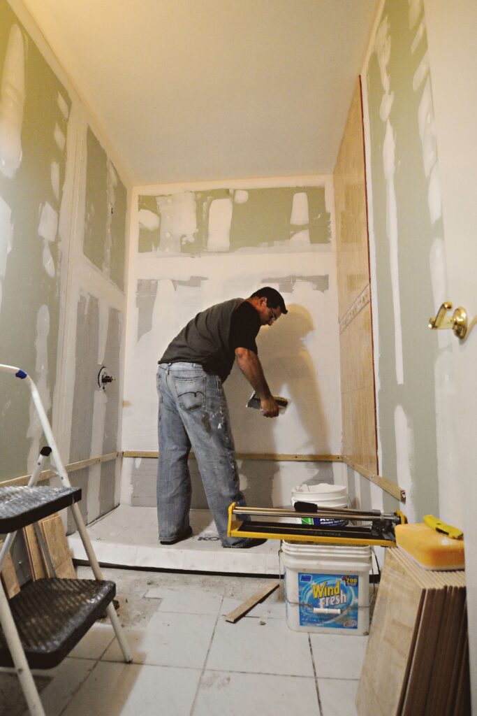 Contractor installing tile during a bathroom bathtub renovation.