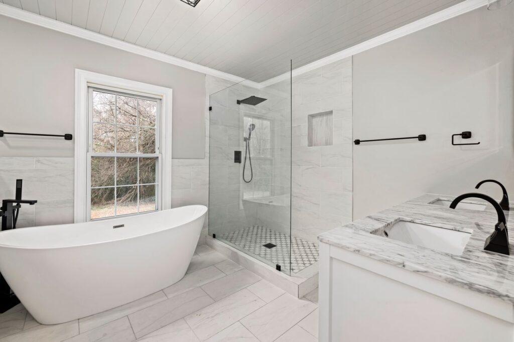 Modern bathroom after a bathtub replacement with a freestanding tub, glass shower, and double vanity.