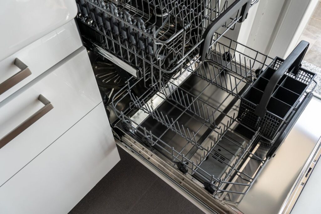 Open dishwasher with empty racks after a wash cycle, showing a clean interior and filter area.
