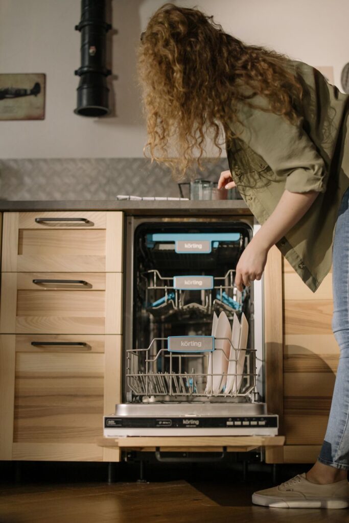 Loading bowls and mugs into a dishwasher as part of regular cleaning and maintenance to help prevent odors.
