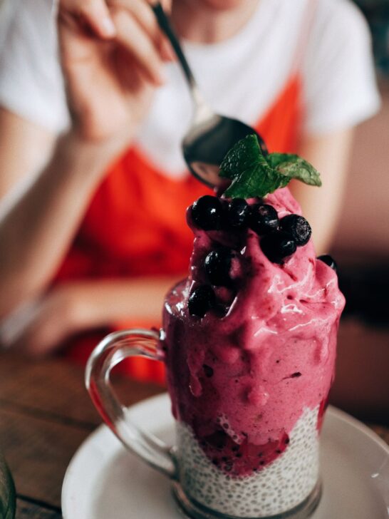 Berry vegan dessert topped with fresh blueberries and mint served over creamy chia pudding in a glass mug.