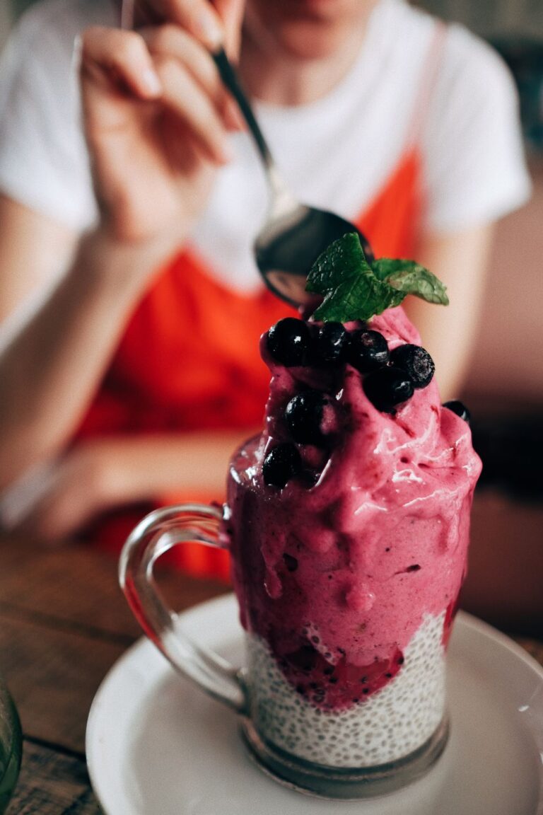 Berry vegan dessert topped with fresh blueberries and mint served over creamy chia pudding in a glass mug.