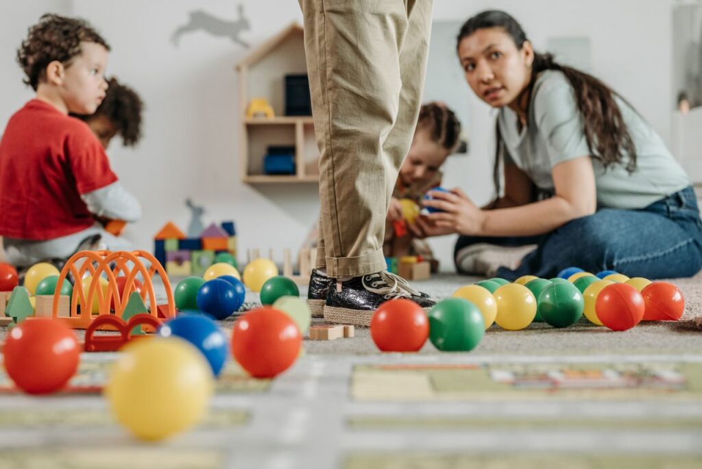 Children playing together in a quality childcare classroom while teachers supervise group activities.
