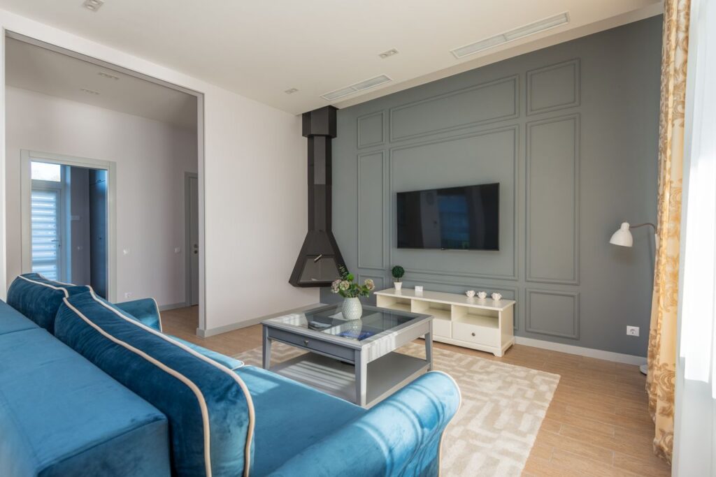 Modern living room with blue sofa, gray accent wall, coffee table, fireplace, and wall-mounted TV