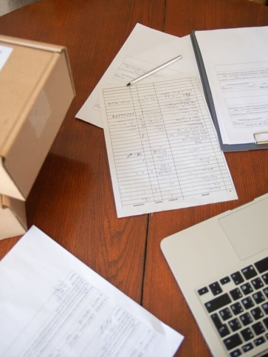 Small business growth paperwork, shipping boxes, and a laptop organized on a desk while preparing business funding documents.