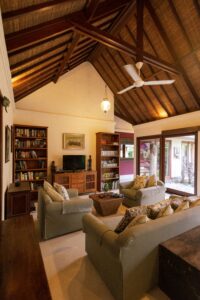 Living room with sofas, armchairs, wood furniture, built-in bookshelves, and a vaulted ceiling.