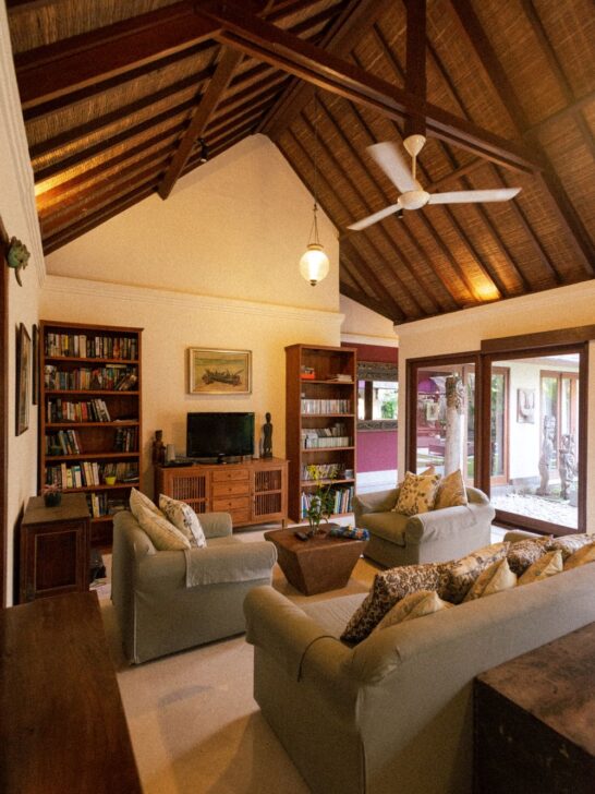 Living room with sofas, armchairs, wood furniture, built-in bookshelves, and a vaulted ceiling.