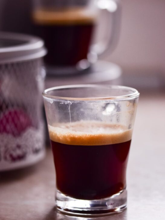 Glass of freshly brewed espresso with a layer of crema on top.