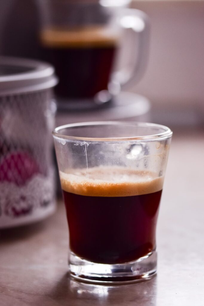 Glass of freshly brewed espresso with a layer of crema on top.